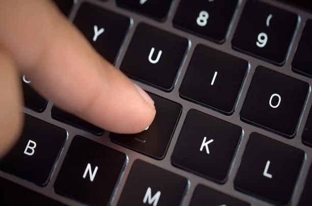 Hands repairing a disassembled laptop on a workbench